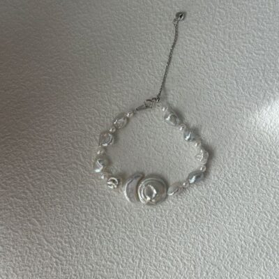 Collier baroque en perles avec pendentif disque rond et présentation latérale