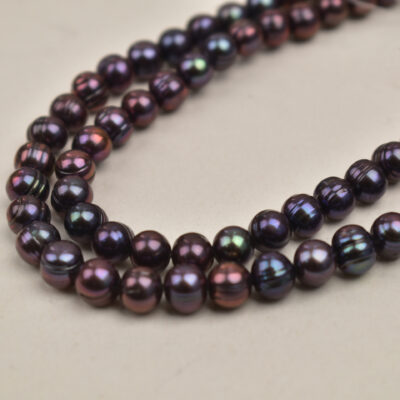 Perlas de patata de 7-8 mm, color negro pavo real, brillo intenso y superficie estriada.