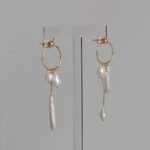 Boucles d'oreilles asymétriques en perles d'eau douce à pompons, mettant en valeur le visage