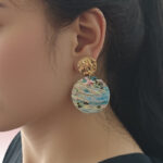 Pendientes colgantes redondos de concha de abulón natural con detalles de disco dorado.