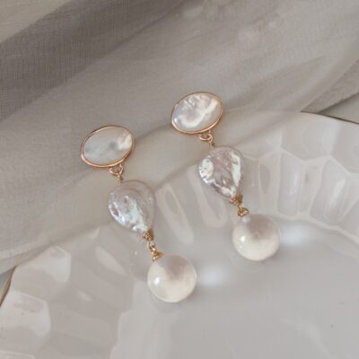 Boucles d'oreilles pendantes géométriques en perles d'eau douce, style baroque naturel, ornées de détails.