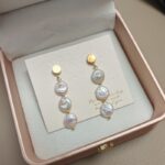 Pendientes colgantes de perlas de agua dulce natural con detalles dorados.